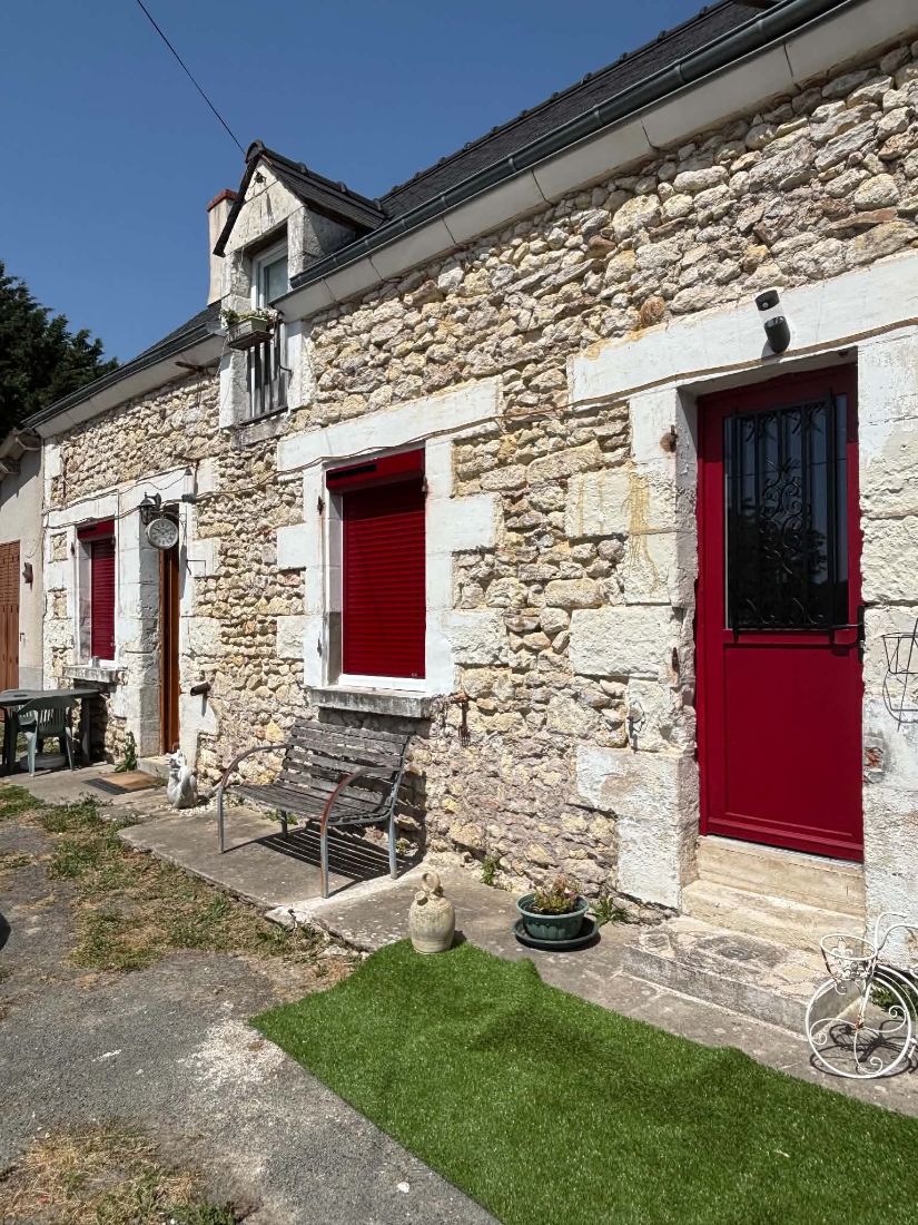 Façade en pierre avec porte d’entrée et fenêtres rouges