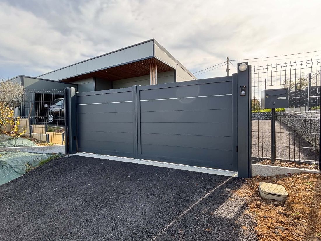 Portail coulissant plein gris anthracite devant un bâtiment récent