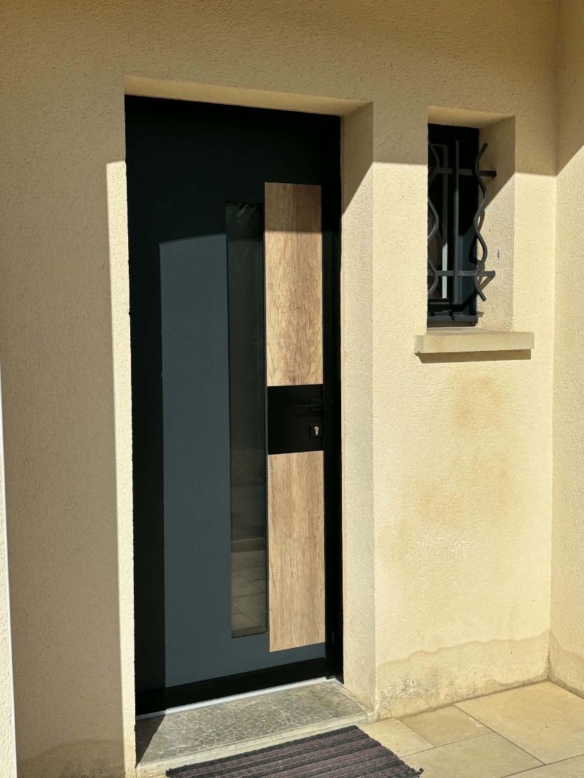 Porte d’entrée gris anthracite avec vitrage latéral sous un porche