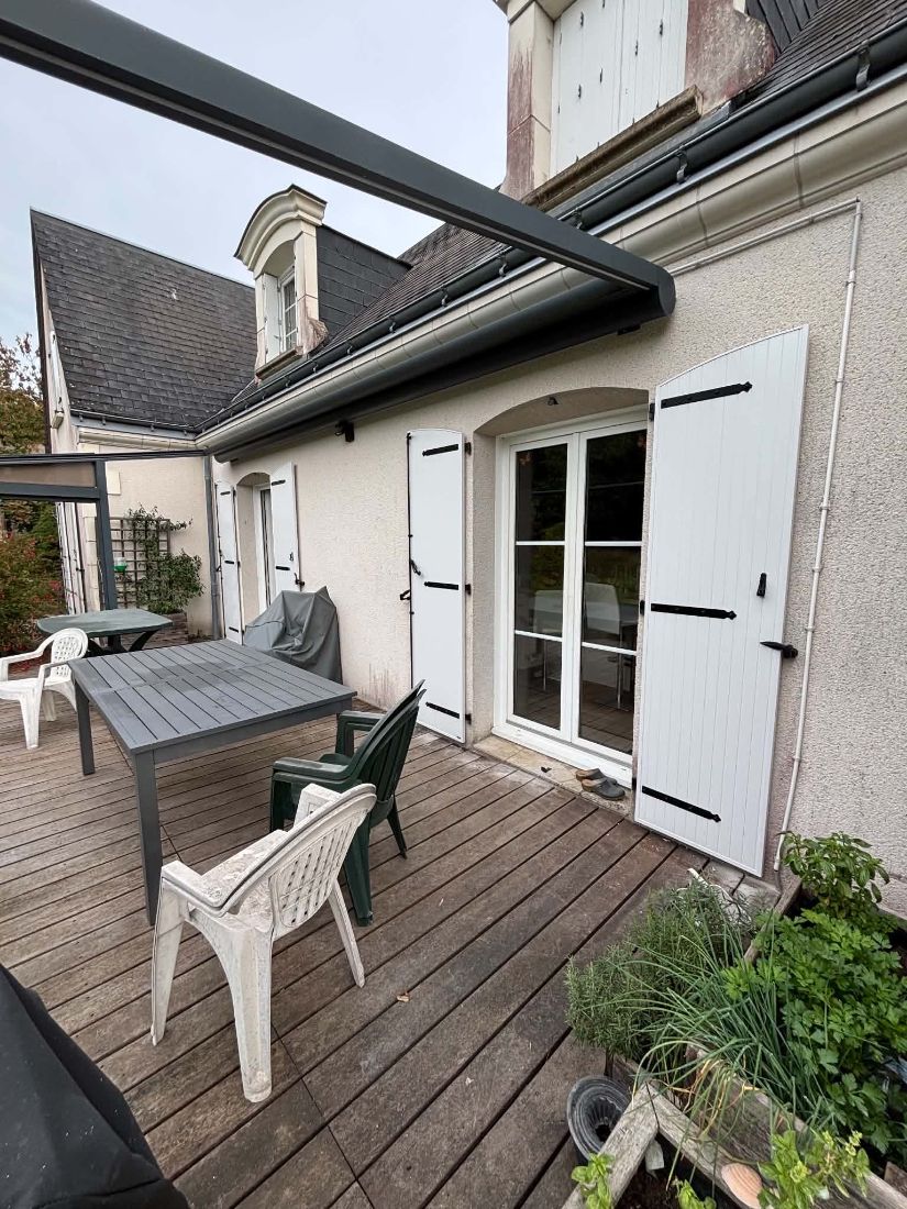 Terrasse et porte-fenêtre encadrée de volets battants blancs